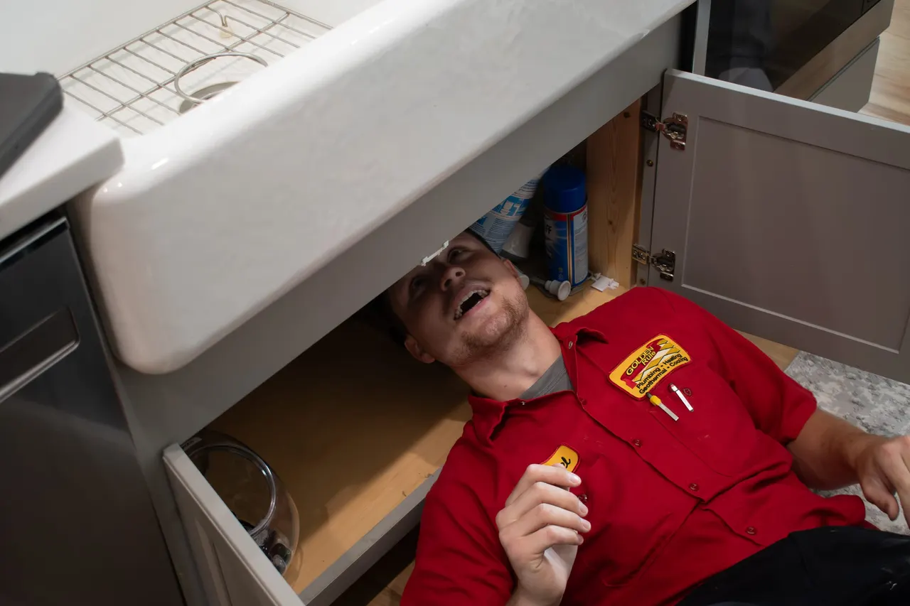 A Golden Rule plumber working under a kitchen sink
