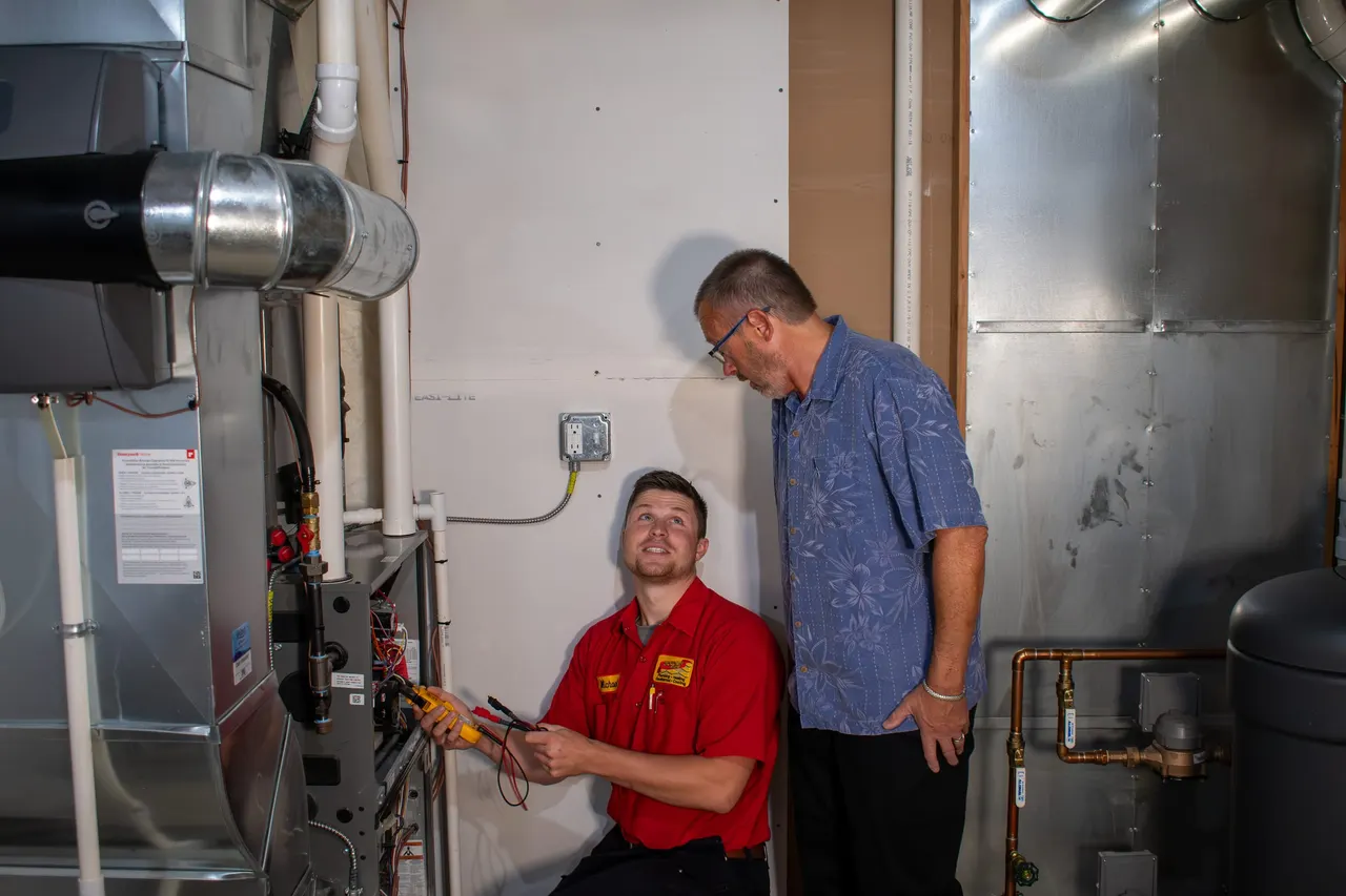A Golden Rule technician testing a furnace while the homeowner watches