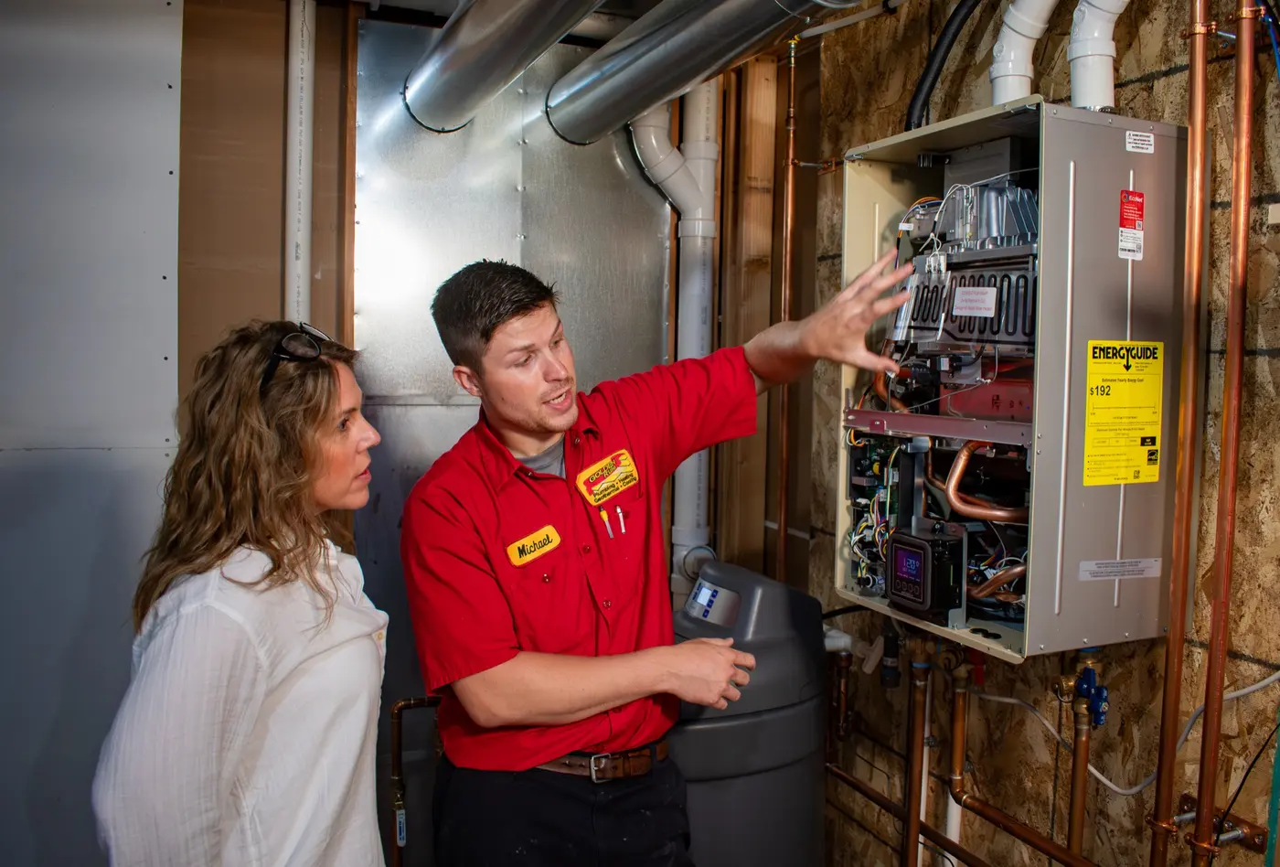 A Golden Rule technician explaining a wall-mounted tankless water heater to a homeowner