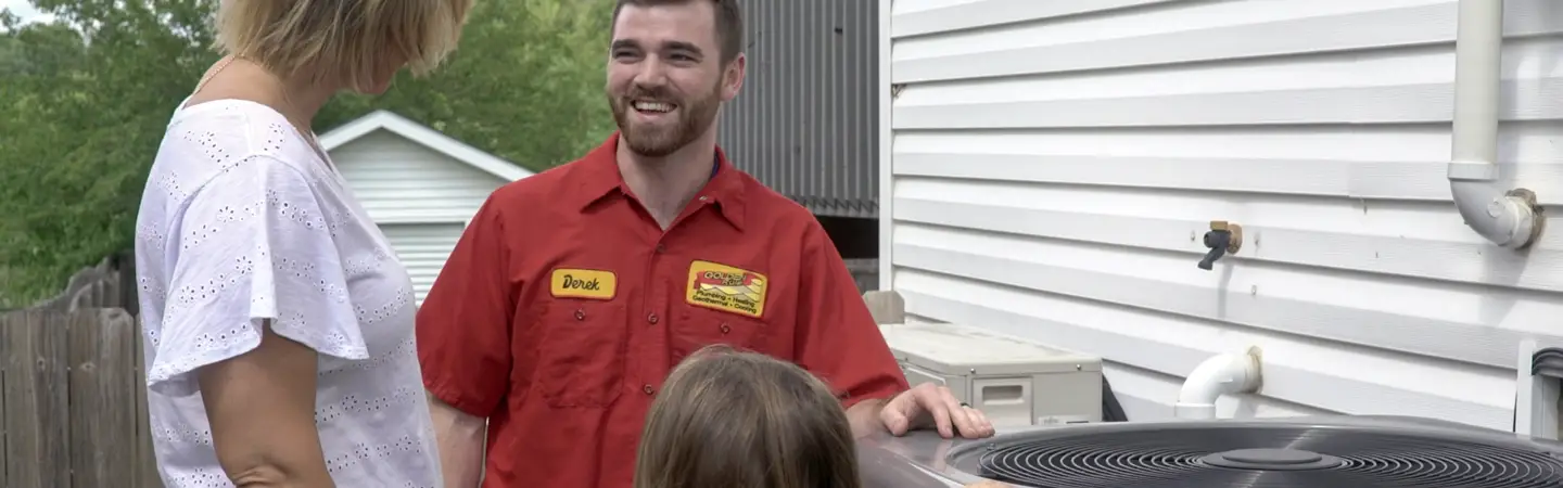 A Golden Rule technician reviewing an outdoor AC unit with homeowners