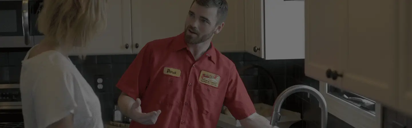 A Golden Rule plumber explaining a repair to a homeowner at their kitchen sink