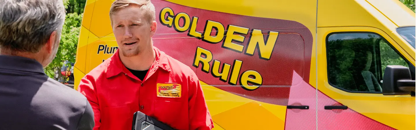 A Golden Rule technician greeting a customer beside a service van